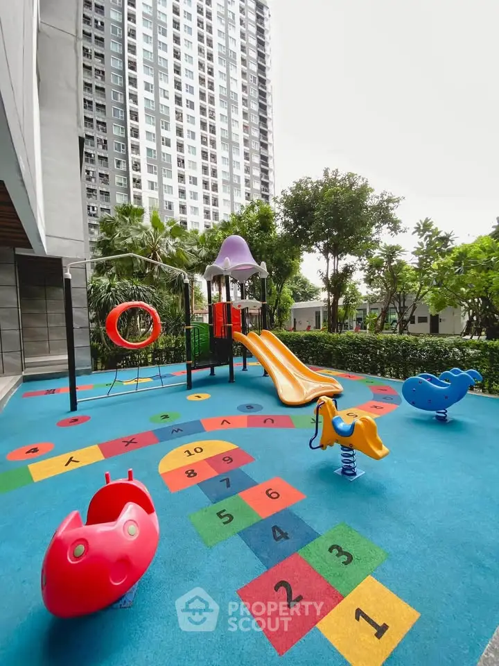 Vibrant playground area in modern residential complex with colorful slides and hopscotch game.