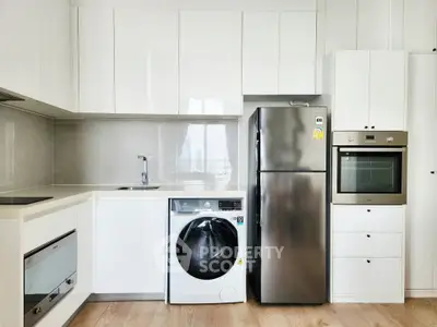 Modern kitchen with sleek appliances including fridge, oven, and washing machine in a bright, minimalist design.
