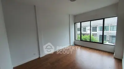Spacious empty room with large window and wooden flooring