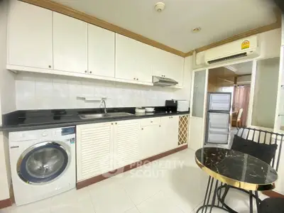 Modern kitchen with sleek cabinets, washing machine, and elegant dining area in a stylish apartment.