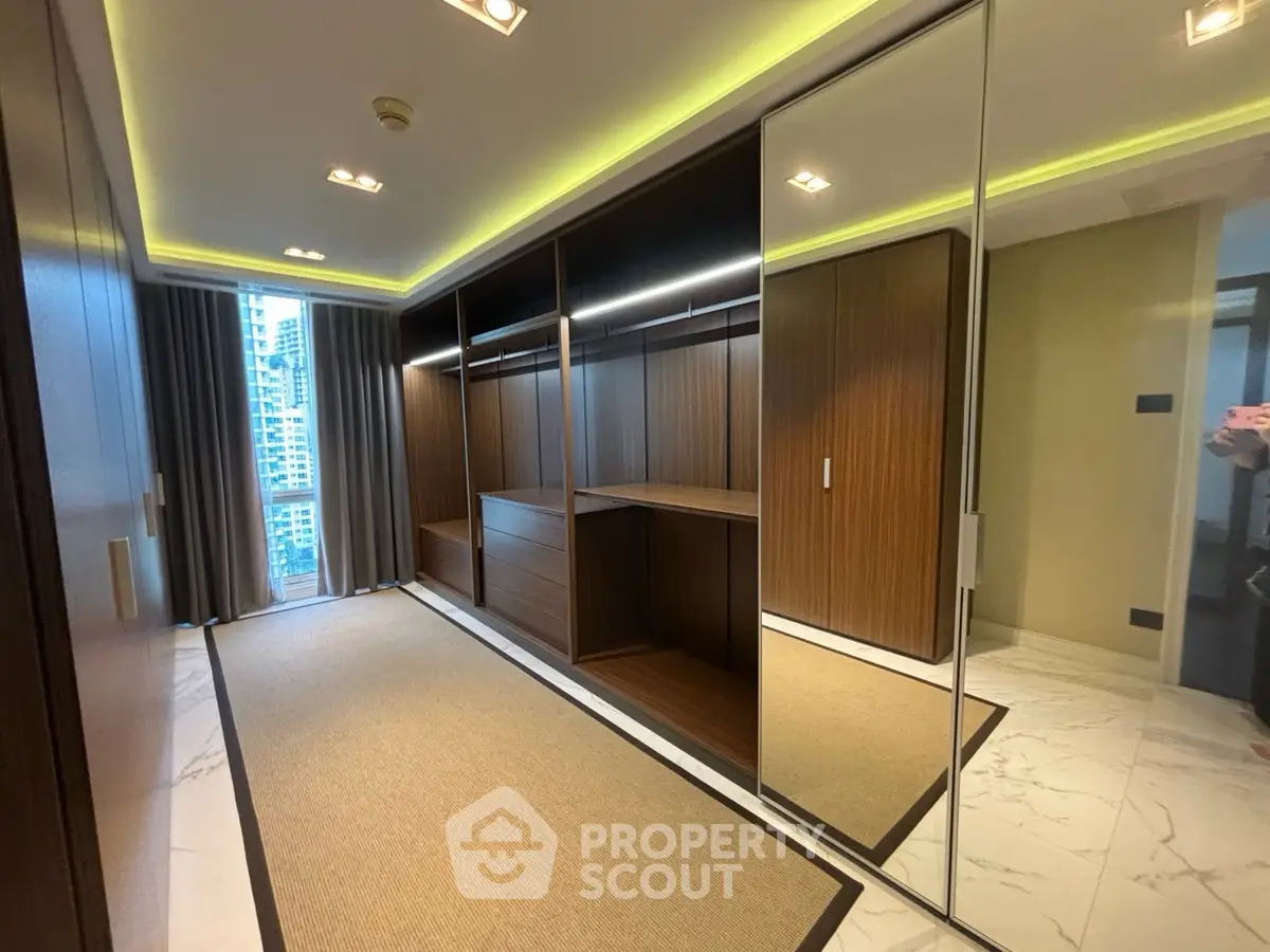 Luxurious walk-in closet with mirrored doors and elegant lighting