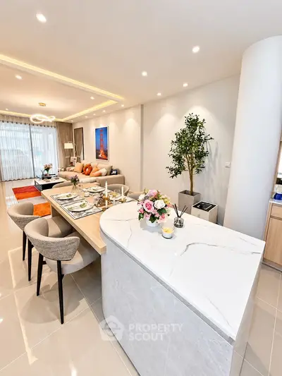 Modern open-plan living room and kitchen with elegant decor and natural lighting.