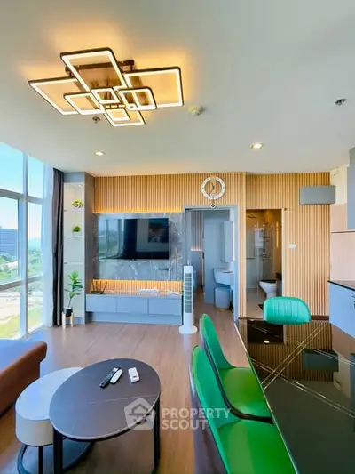 Modern living room with stylish lighting and open layout, featuring a large TV and scenic window view.