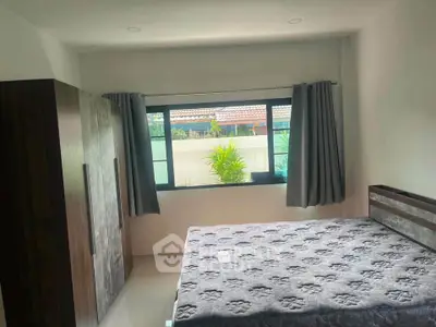 Spacious bedroom with large window and modern furnishings in a serene setting.