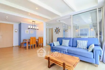 Spacious living room with blue sofa and wooden dining set in modern apartment