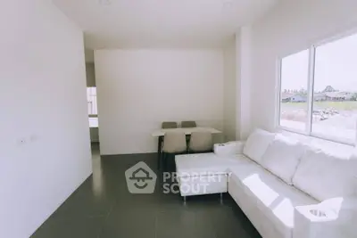 Bright living room with modern white sofa and dining area, large window with natural light