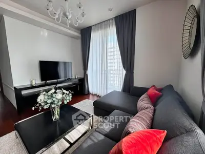 Modern living room with stylish decor, featuring a sleek sectional sofa, large TV, and elegant chandelier.