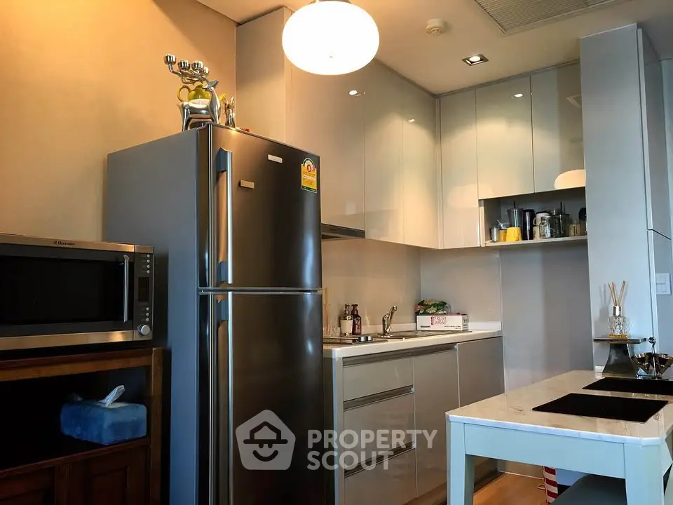 Modern kitchen with sleek cabinets, stainless steel fridge, and elegant dining area.