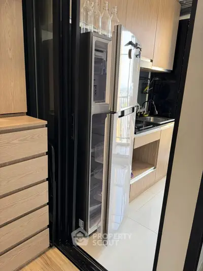 Modern kitchen with sleek fridge and wooden cabinetry, showcasing contemporary design and functionality.