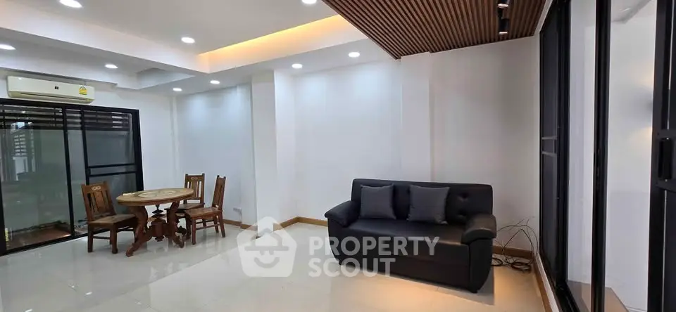 Spacious modern living room with sleek design and ample natural light, featuring a cozy seating area and dining space.