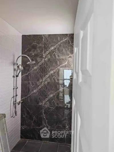 Modern bathroom with elegant marble wall and sleek shower fixture