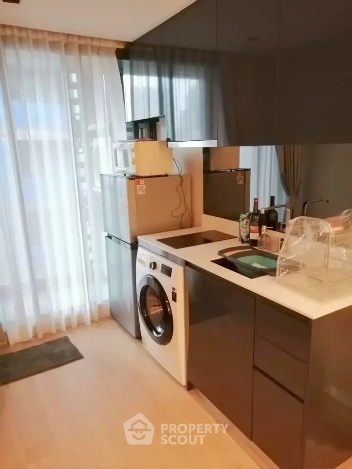 Modern kitchen with sleek cabinetry, washing machine, and ample natural light from large windows.