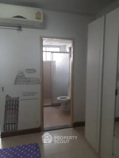 Cozy bedroom with ensuite bathroom, featuring air conditioning and modern wardrobe.