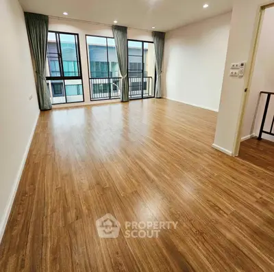 Spacious empty living room with wooden flooring and large windows