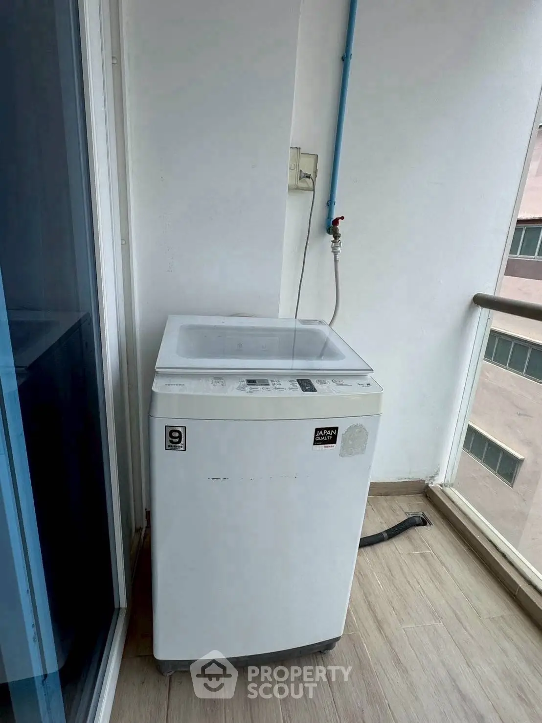 Compact washing machine on a balcony with city view, ideal for urban living.