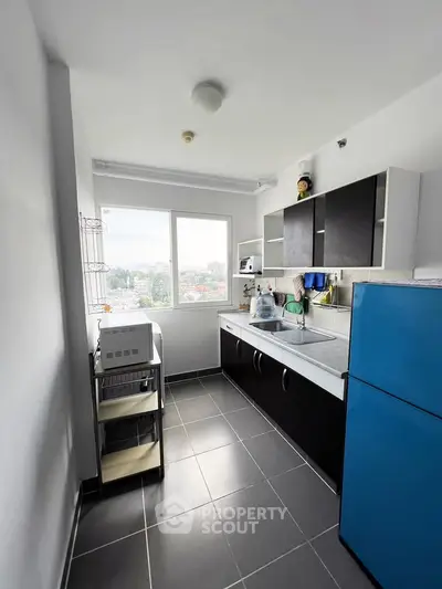 Modern kitchen with sleek cabinets and large window offering city views.
