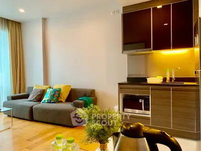 Modern living room with kitchenette, featuring cozy sofa and stylish decor.