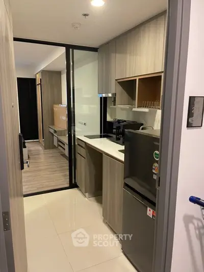 Modern compact kitchen with sleek cabinetry and appliances in a stylish apartment.