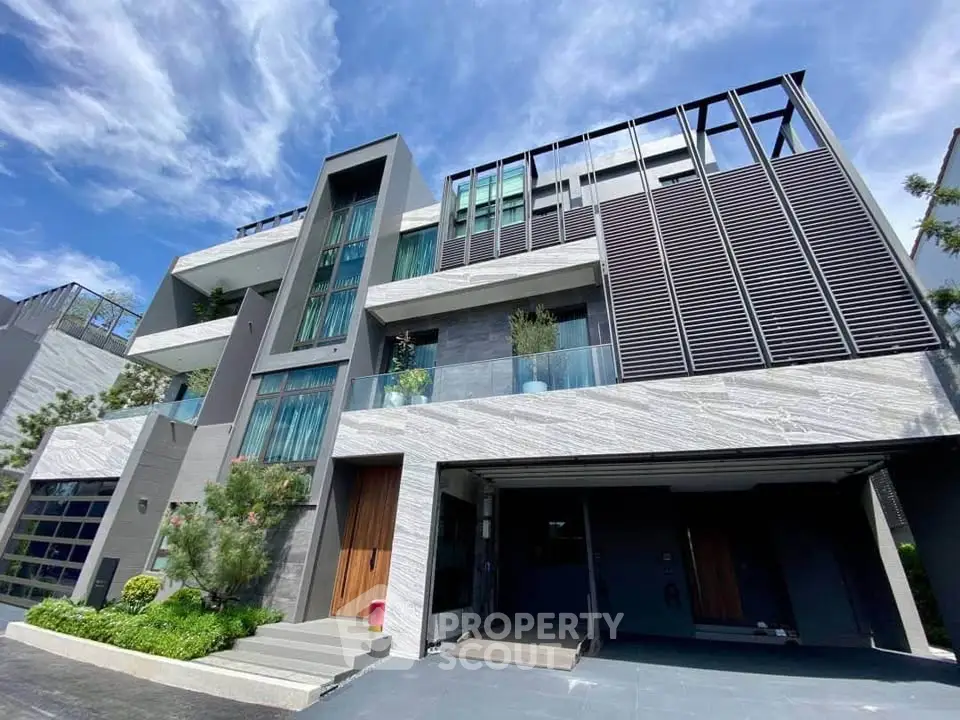 Modern multi-story building with sleek design and large windows, featuring a spacious garage and lush greenery.