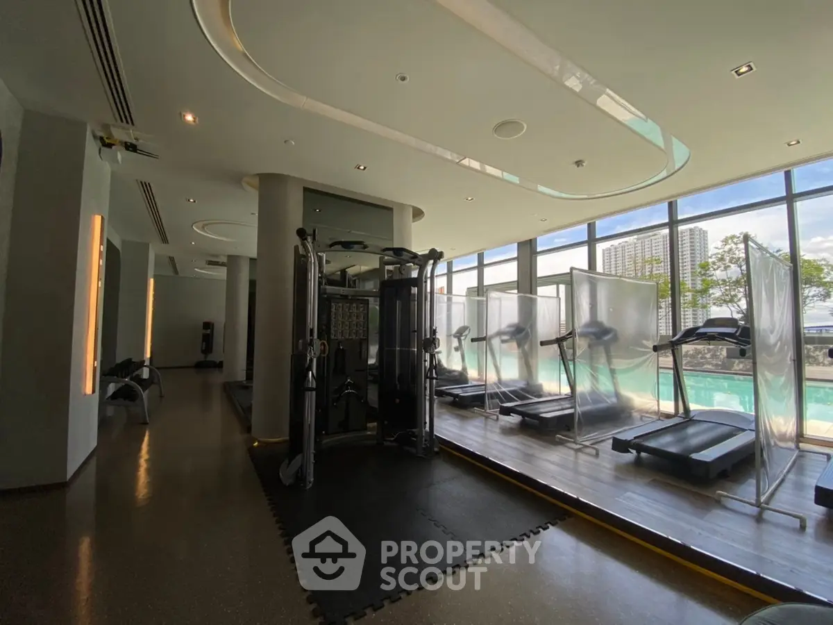 Luxurious gym with modern equipment and pool view in upscale residential building.