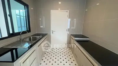Modern kitchen with sleek countertops and tiled flooring, featuring a large window for natural light.