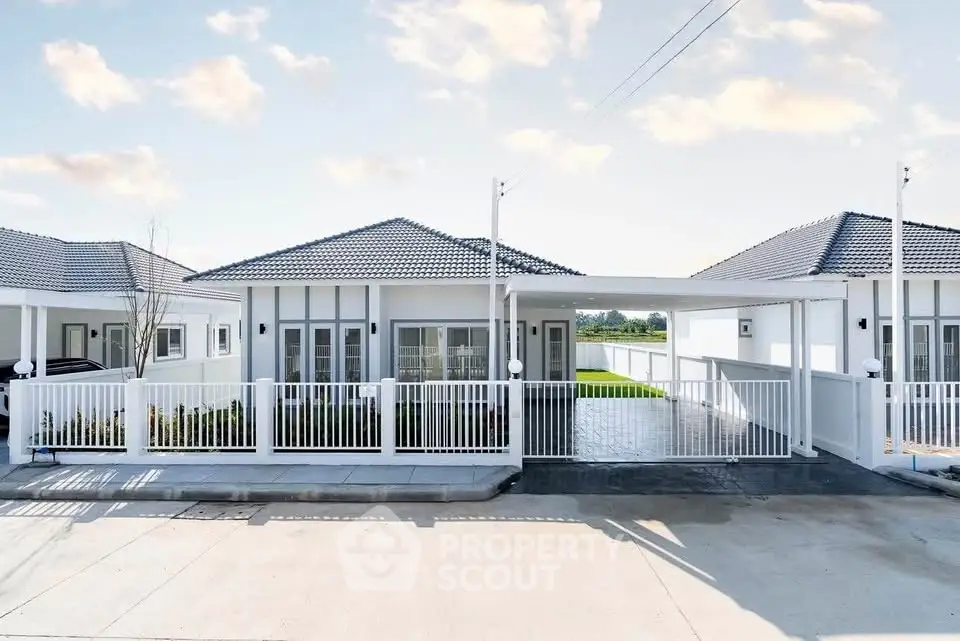 Charming modern bungalow with white picket fence and spacious driveway in serene neighborhood.