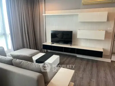 Modern living room with sleek furniture and wall-mounted TV, featuring elegant gray tones and natural light.