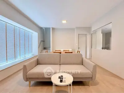 Spacious modern living room with stylish sofa and natural light, perfect for relaxation and entertaining.