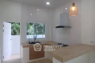 Modern kitchen with open layout and gas stove, featuring sleek countertops and stylish lighting.