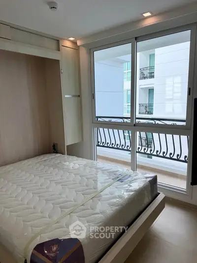 Modern bedroom with large window and balcony view in a stylish apartment.