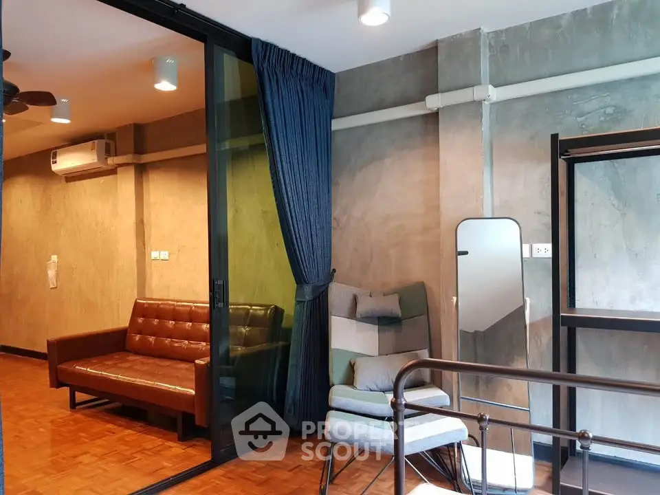 Stylish modern living room with leather sofa and cozy seating area, featuring industrial concrete walls and wooden flooring.