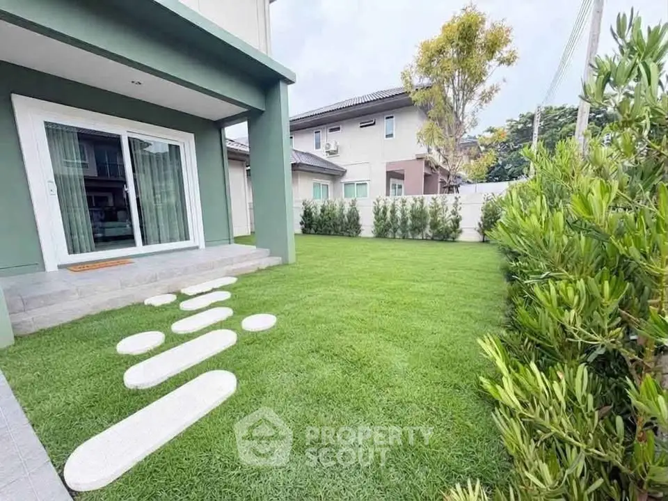 Charming backyard with lush green lawn and modern stepping stones leading to patio.