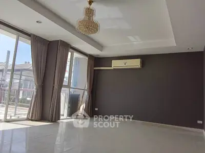 Spacious living room with large windows and elegant chandelier in modern apartment.