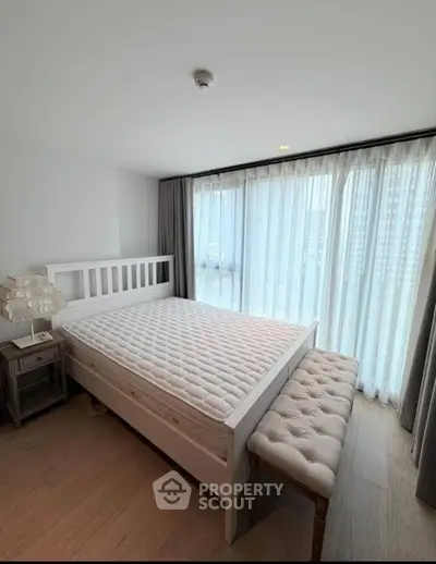 Spacious bedroom with large windows and elegant furnishings in modern apartment.