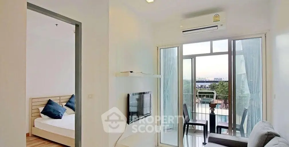Modern apartment with balcony and city view, featuring a cozy living room and adjacent bedroom.