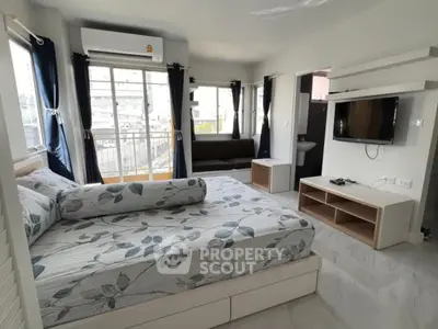 Modern bedroom with balcony and TV, featuring stylish decor and natural light.