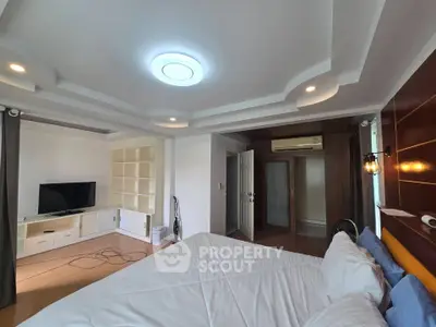 Spacious bedroom with modern ceiling design and built-in shelving, featuring a cozy ambiance.