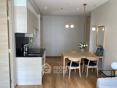 Modern open-layout kitchen and dining area with elegant lighting and wooden flooring.