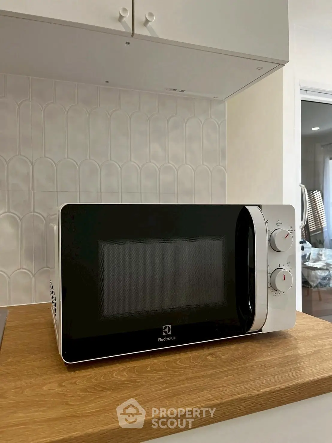 Modern kitchen with sleek microwave on wooden countertop, featuring stylish tile backsplash.