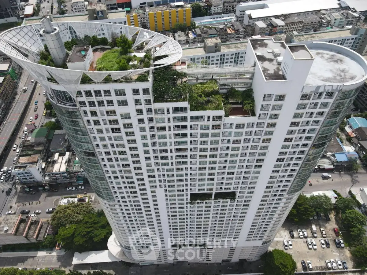 Stunning aerial view of a modern high-rise building with lush rooftop garden in urban setting.