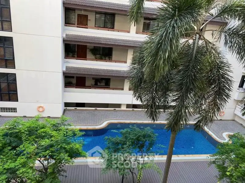 Stunning apartment complex with a serene pool and lush greenery, perfect for relaxation and leisure.