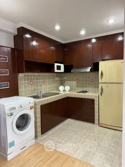 Spacious kitchen with wooden cabinets, washing machine, and modern appliances.
