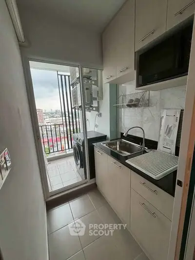 Compact kitchen with balcony view, featuring modern appliances and efficient storage solutions.