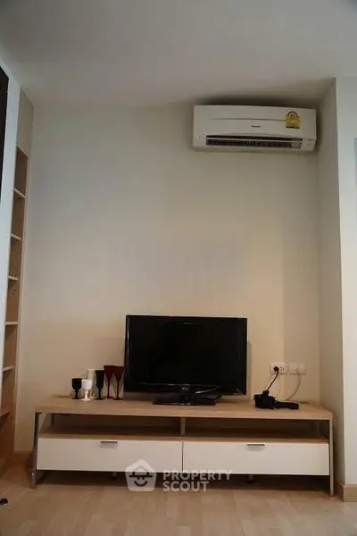 Modern living room with sleek TV setup and air conditioning unit.