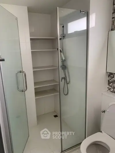 Modern bathroom with glass shower enclosure and built-in shelving