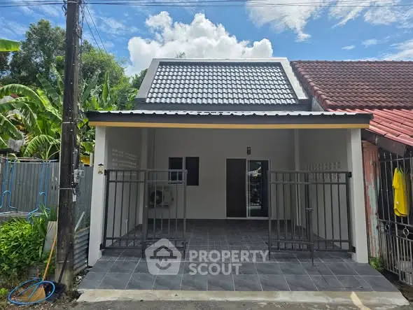 Charming single-story home with modern roof design and gated front patio, perfect for cozy living.