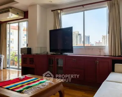 Spacious living room with large windows and city view, featuring a cozy seating area and entertainment center.