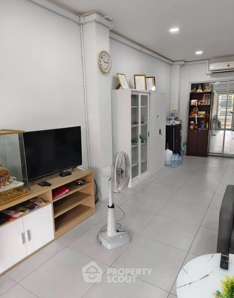 Spacious living room with modern decor and ample natural light, featuring a TV unit and stylish storage solutions.