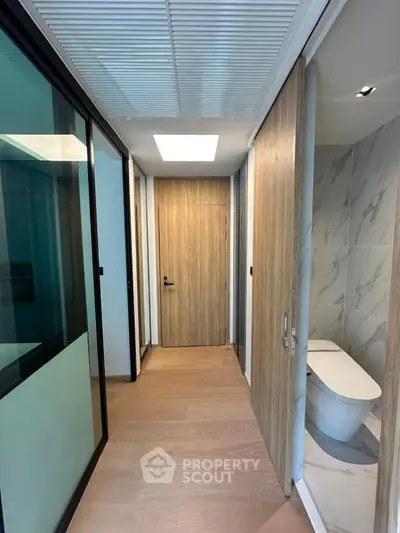 Modern hallway with wooden flooring and sleek bathroom entrance