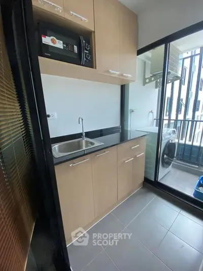 Compact kitchen with modern appliances and balcony view